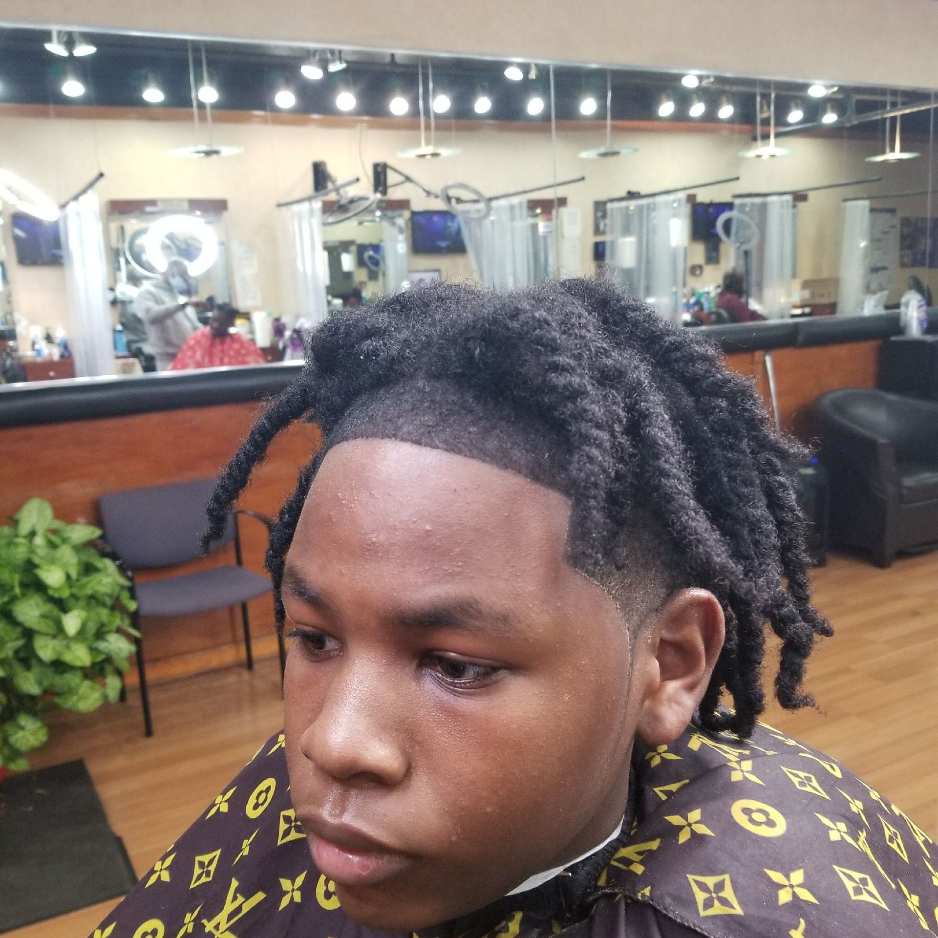 Person with dreadlocks, receiving a haircut in a salon.