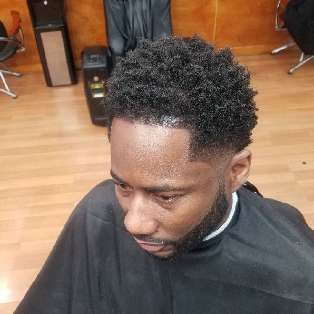 Man with a short, textured haircut and a tapered fade at a barbershop.
