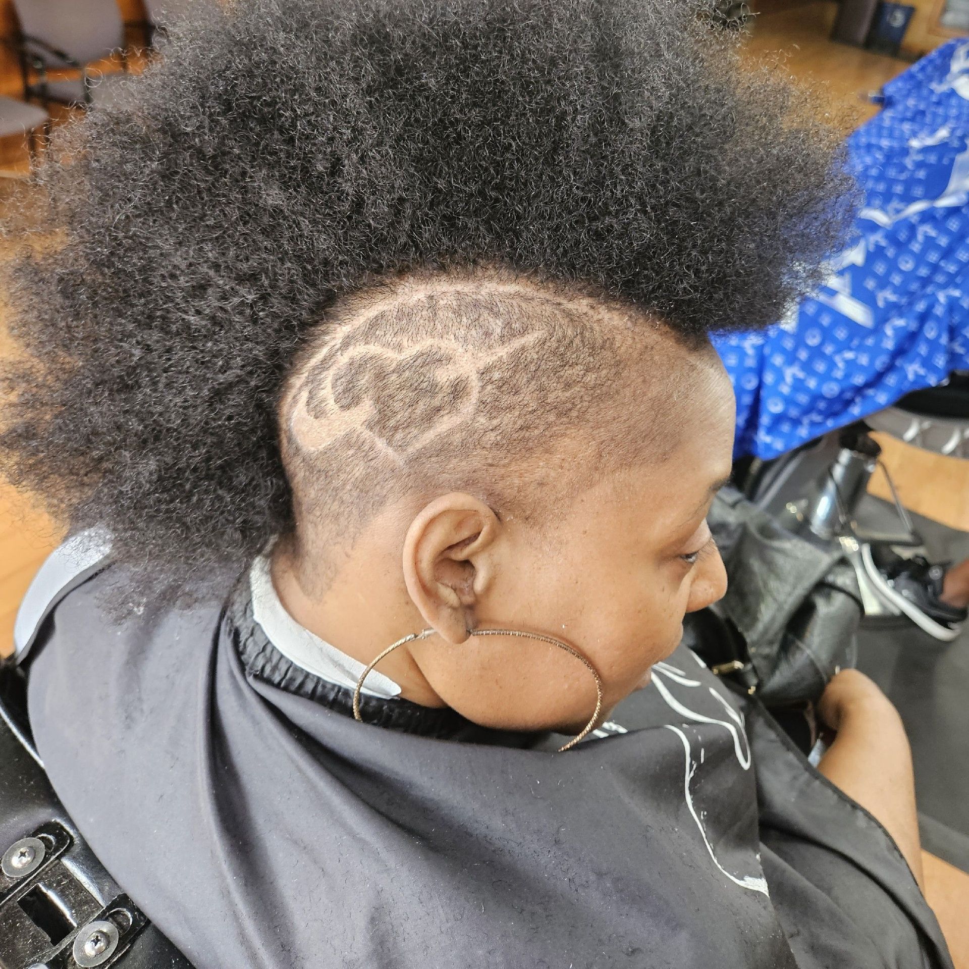 Person with a mohawk hairstyle, shaved sides with a heart design.