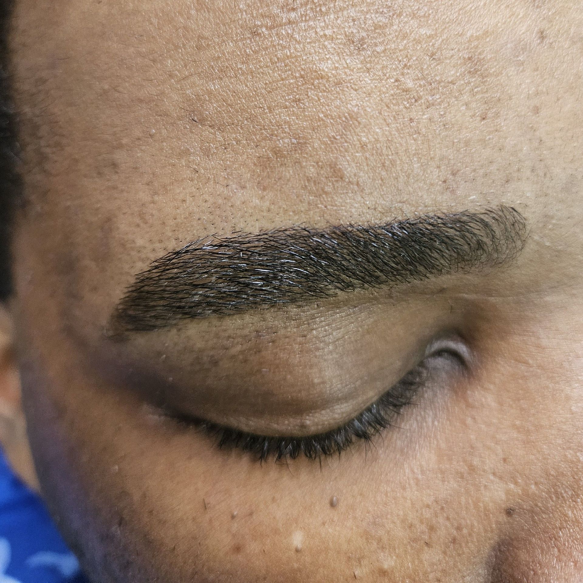 Close-up of a person's closed eye and eyebrow. The eyebrow is dark and defined.
