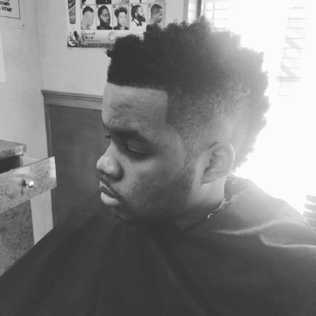 Man with a fade haircut in a barber shop, looking to the side.
