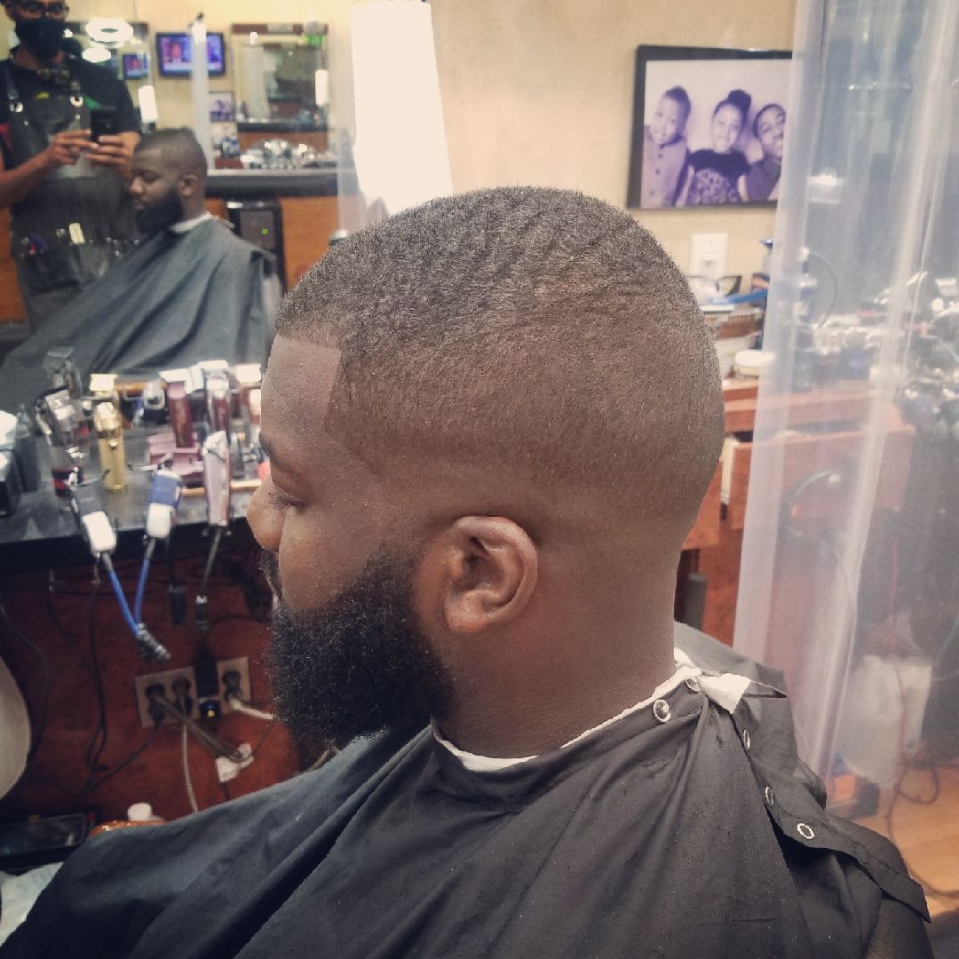 Man with a short haircut and beard in a barber's chair, getting a haircut.