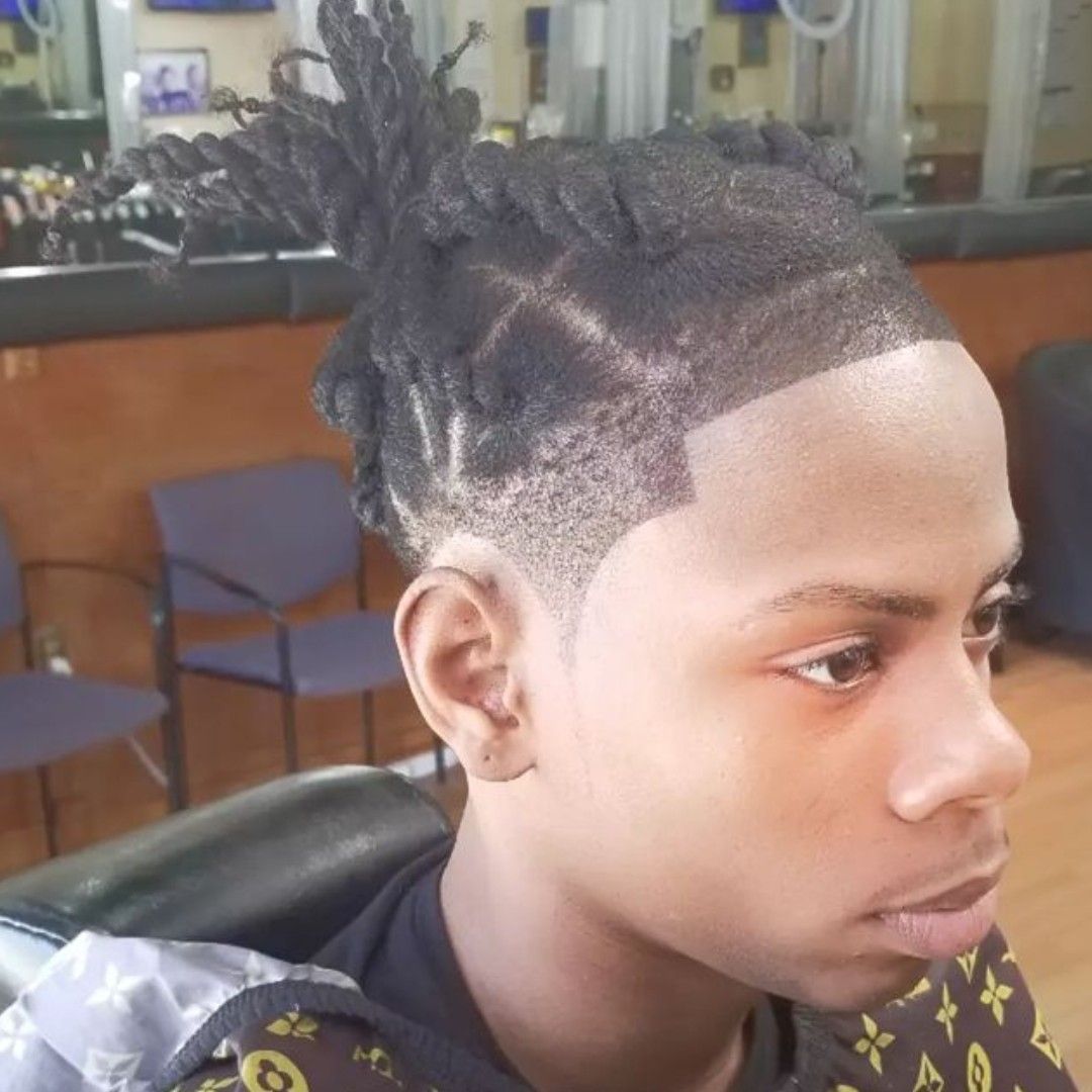 Person with dark hair and a detailed haircut, posing in a barber shop.