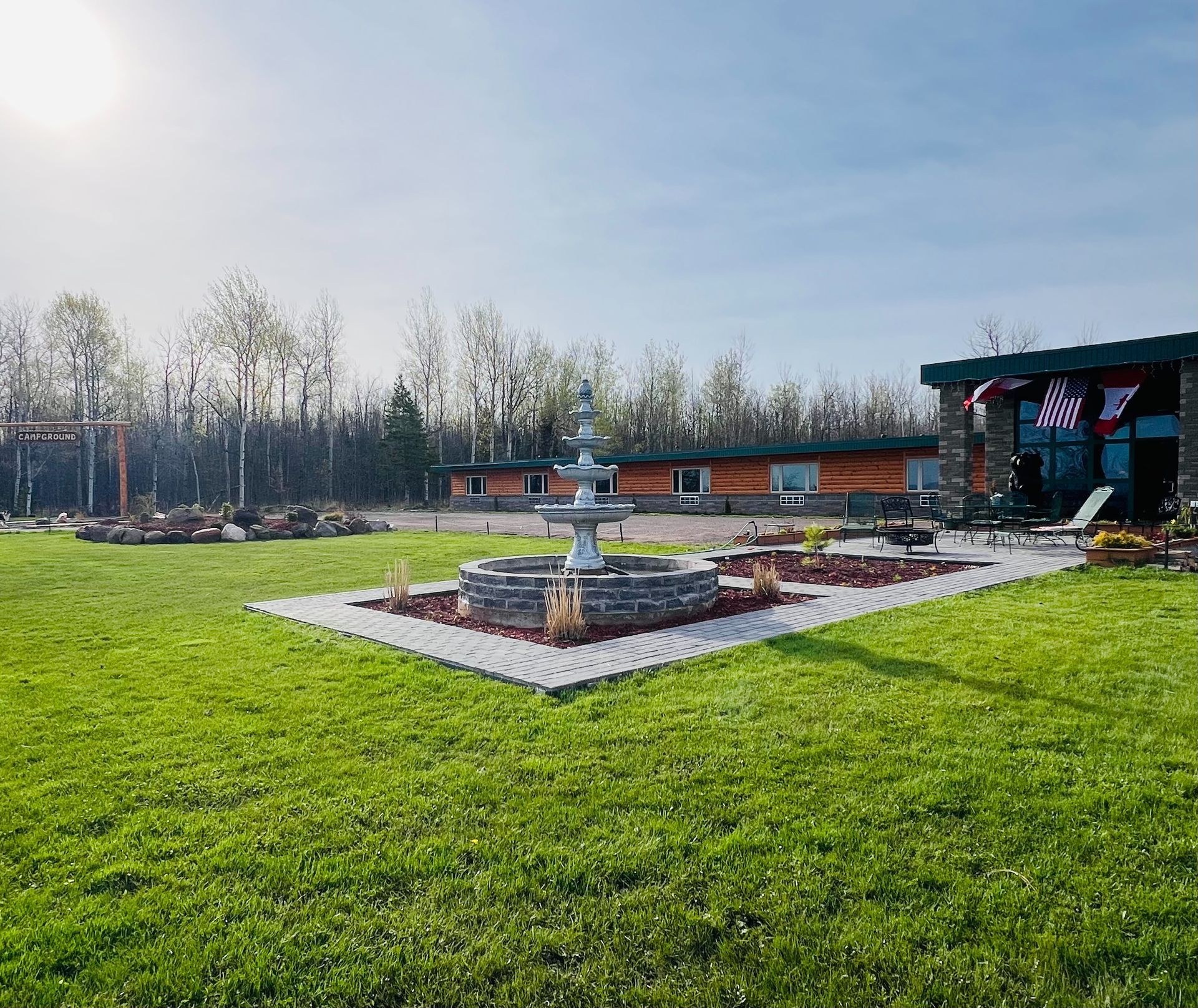 A large lawn with a fountain in the middle of it and a house in the background.
