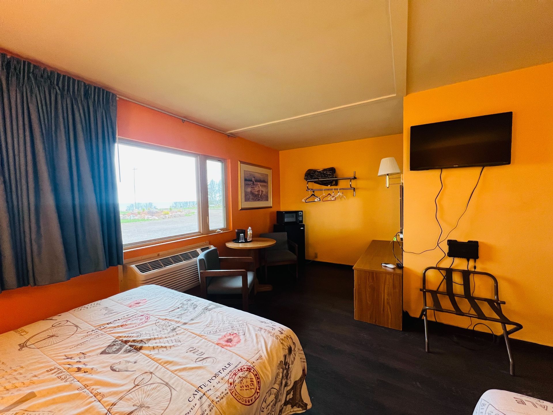 A hotel room with a bed , desk , chair and television.