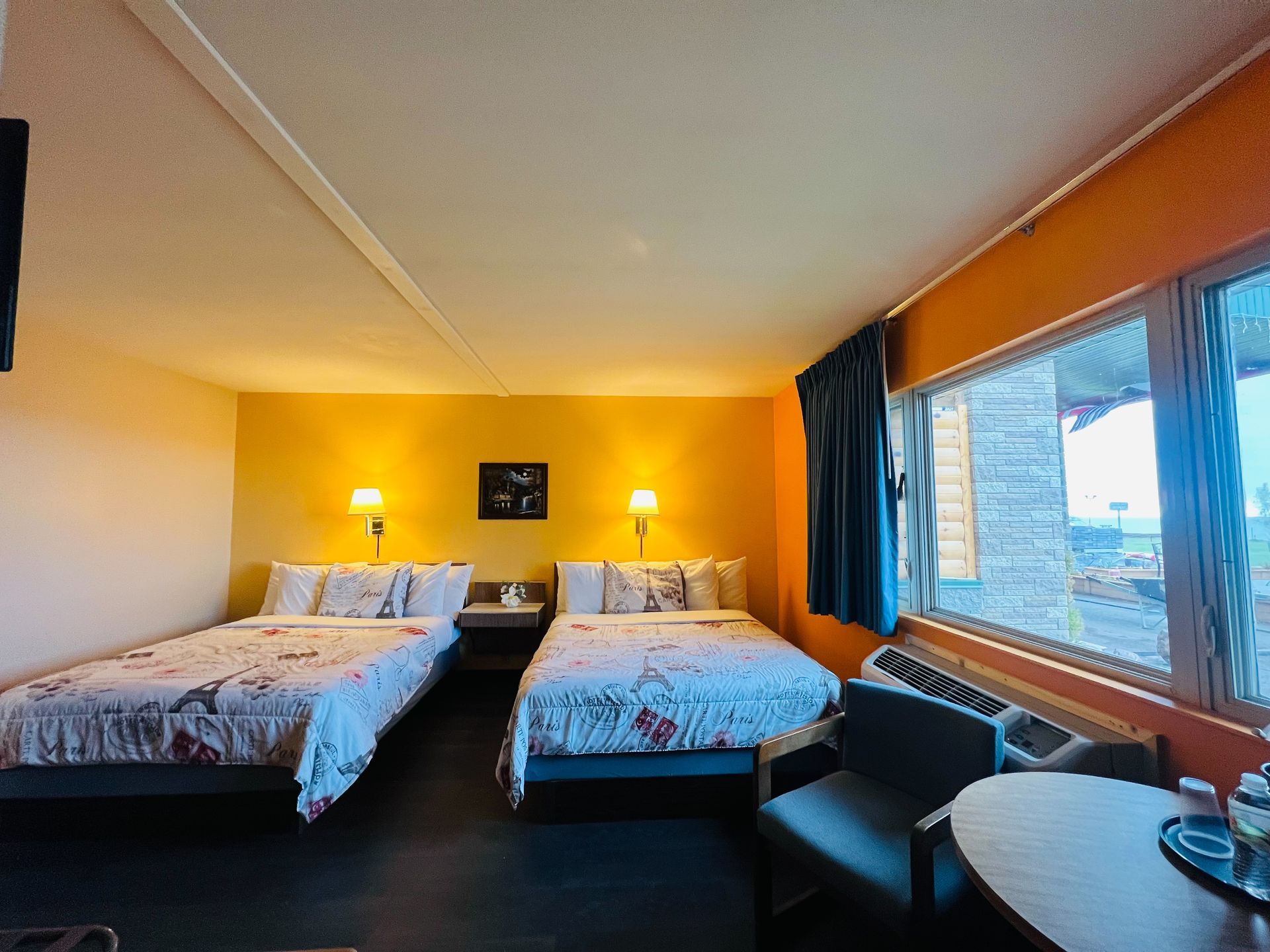 A hotel room with two beds , a table and a chair.