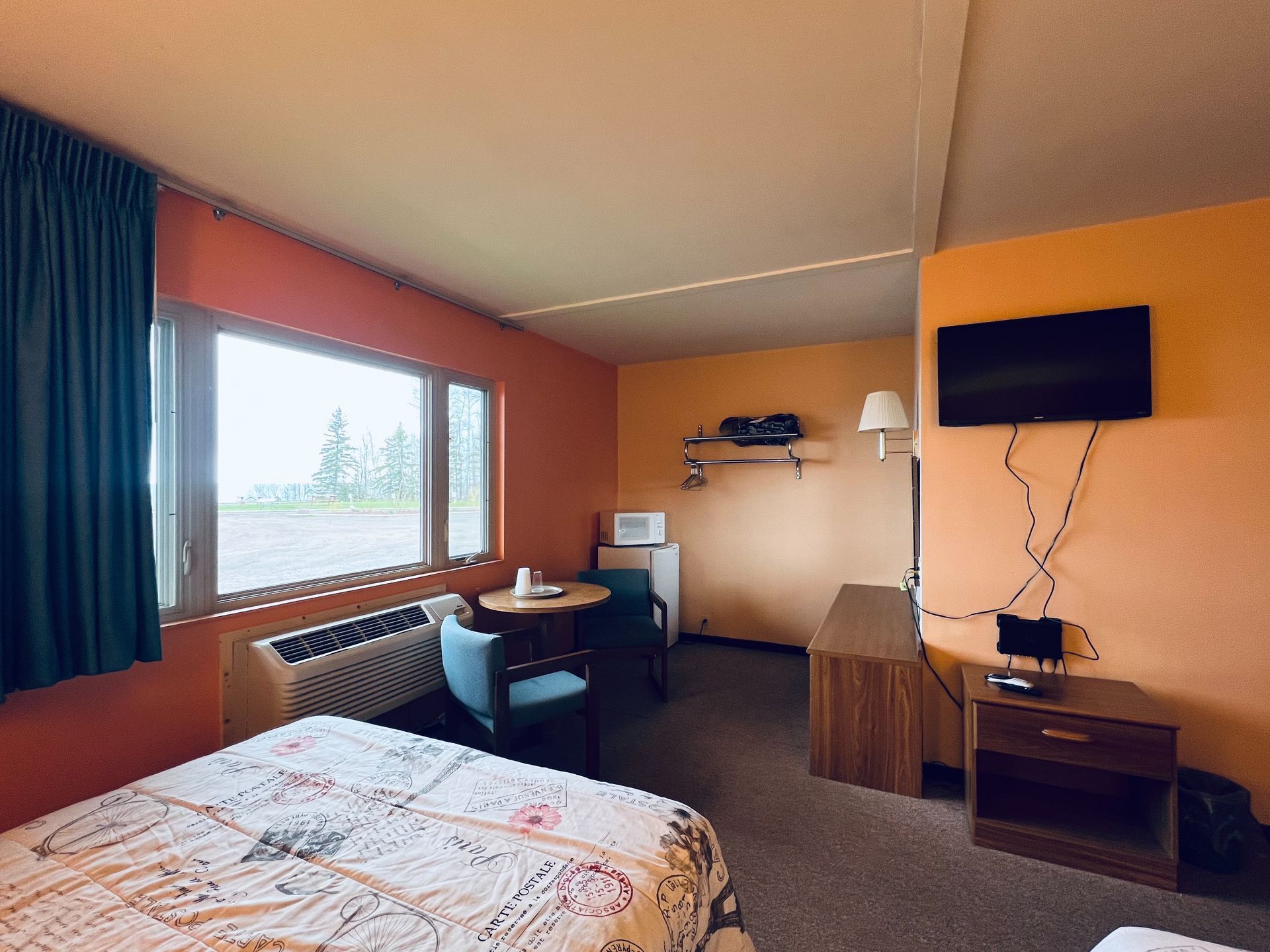 A hotel room with a bed , chairs , table and television.