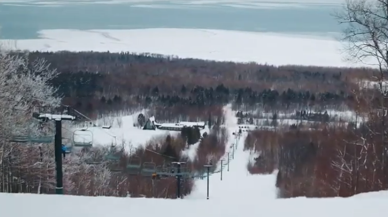 A ski lift is going up a snow covered mountain.