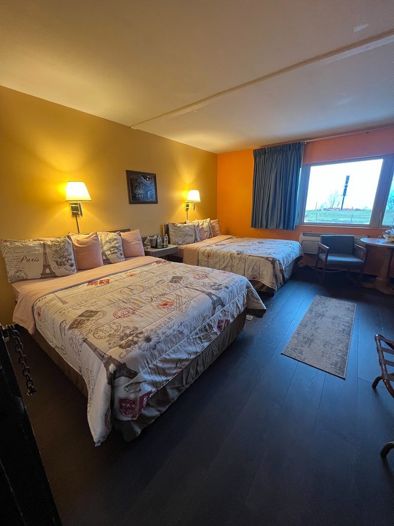 A hotel room with two beds and a large window.