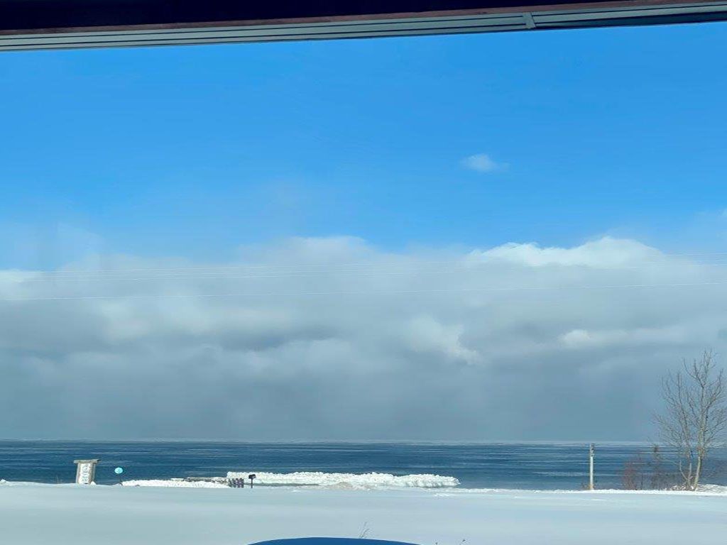 A view of the ocean from a snowy field