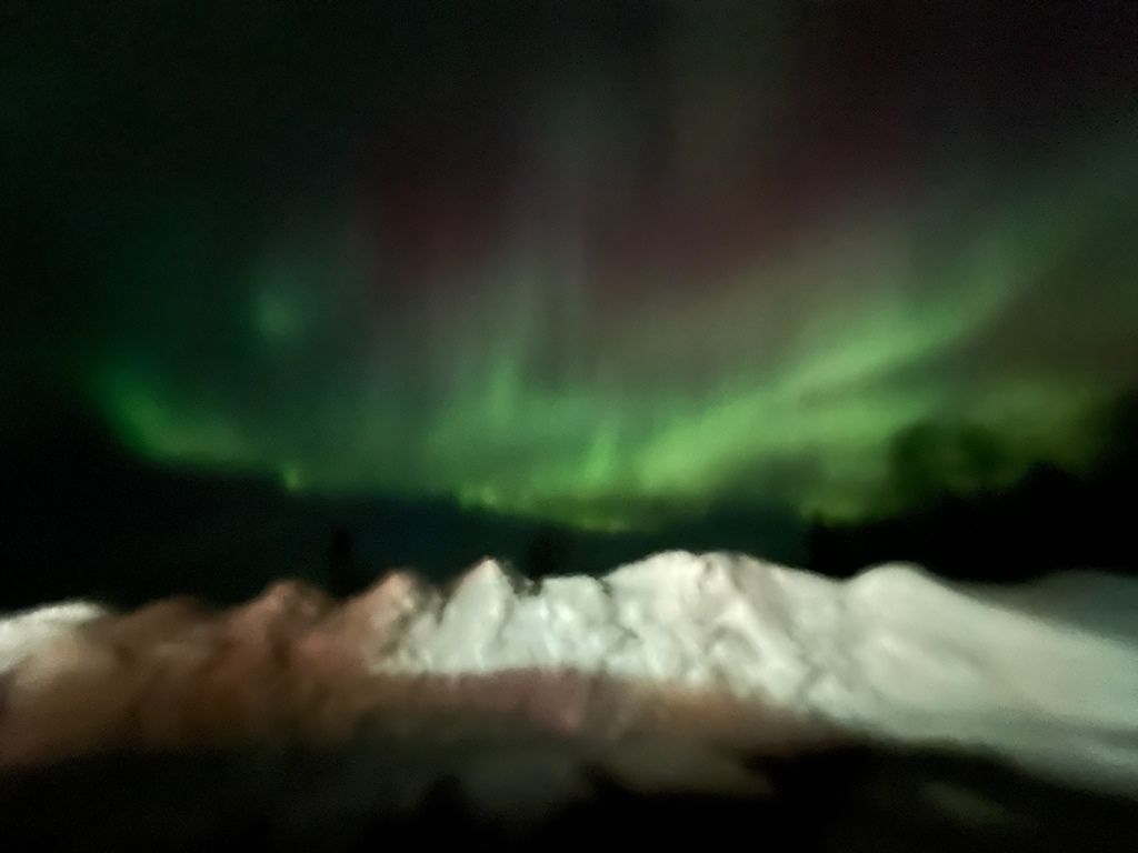 The aurora borealis is visible over a snowy mountain range