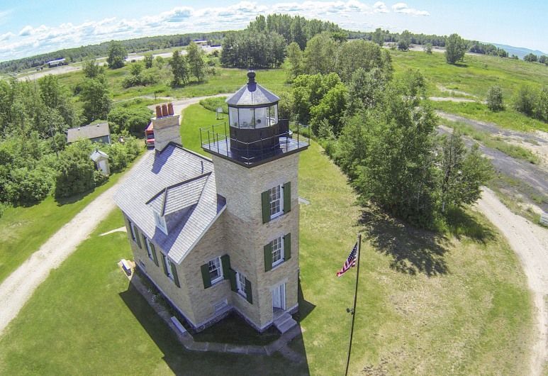 An aerial view of a lighthouse in the middle of a field