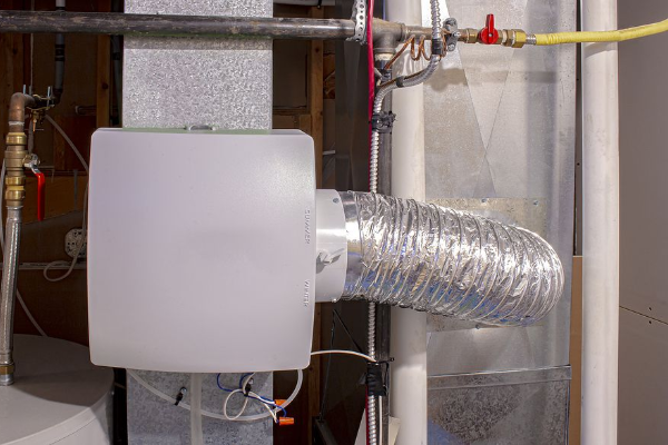 Humidifier attached to ductwork with flexible duct, in a basement setting.