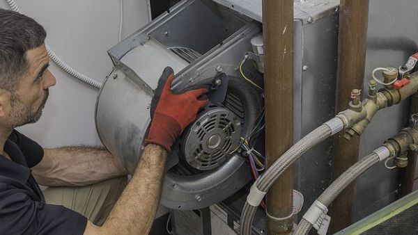 A man wearing red gloves is working on an air conditioner.