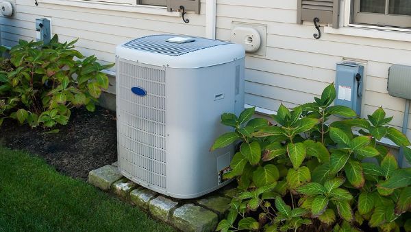 A white air conditioner is sitting on the side of a house.