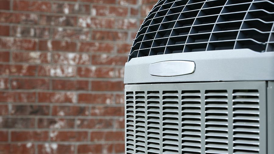 An air conditioner is sitting in front of a brick wall.