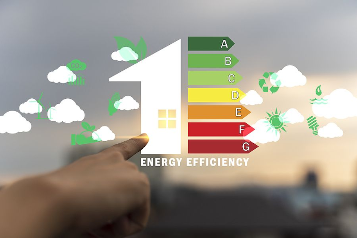 Person's finger points at an energy-efficient house icon, next to a color-coded energy efficiency scale.
