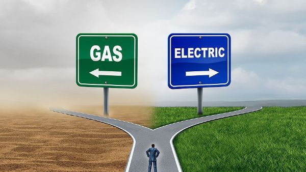 A man is standing at a crossroad between gas and electric signs