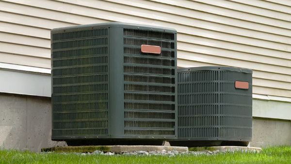 two air conditioners are sitting on the side of a house .