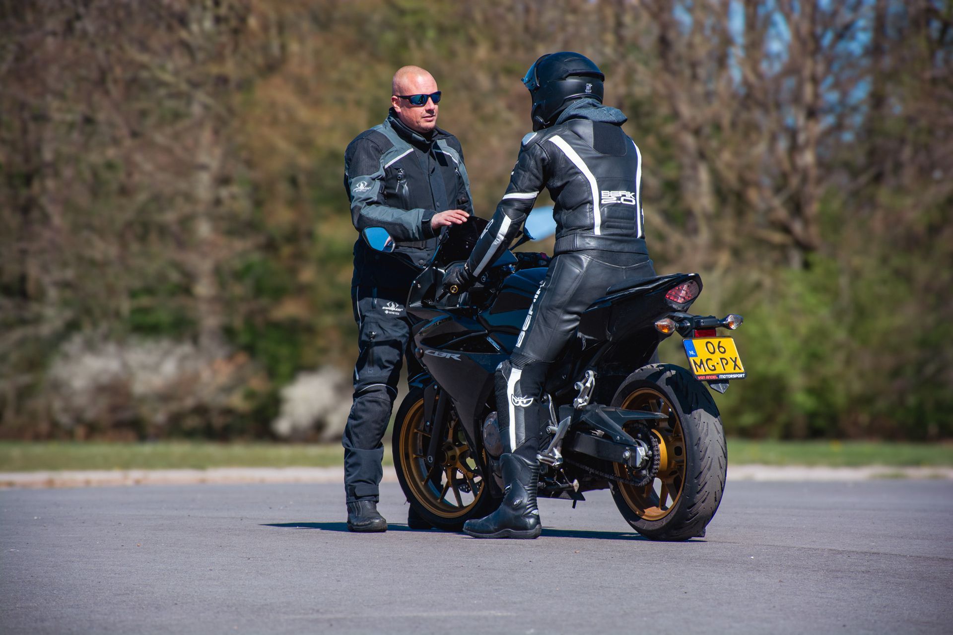 Een man praat met een vrouw op een motorfiets.