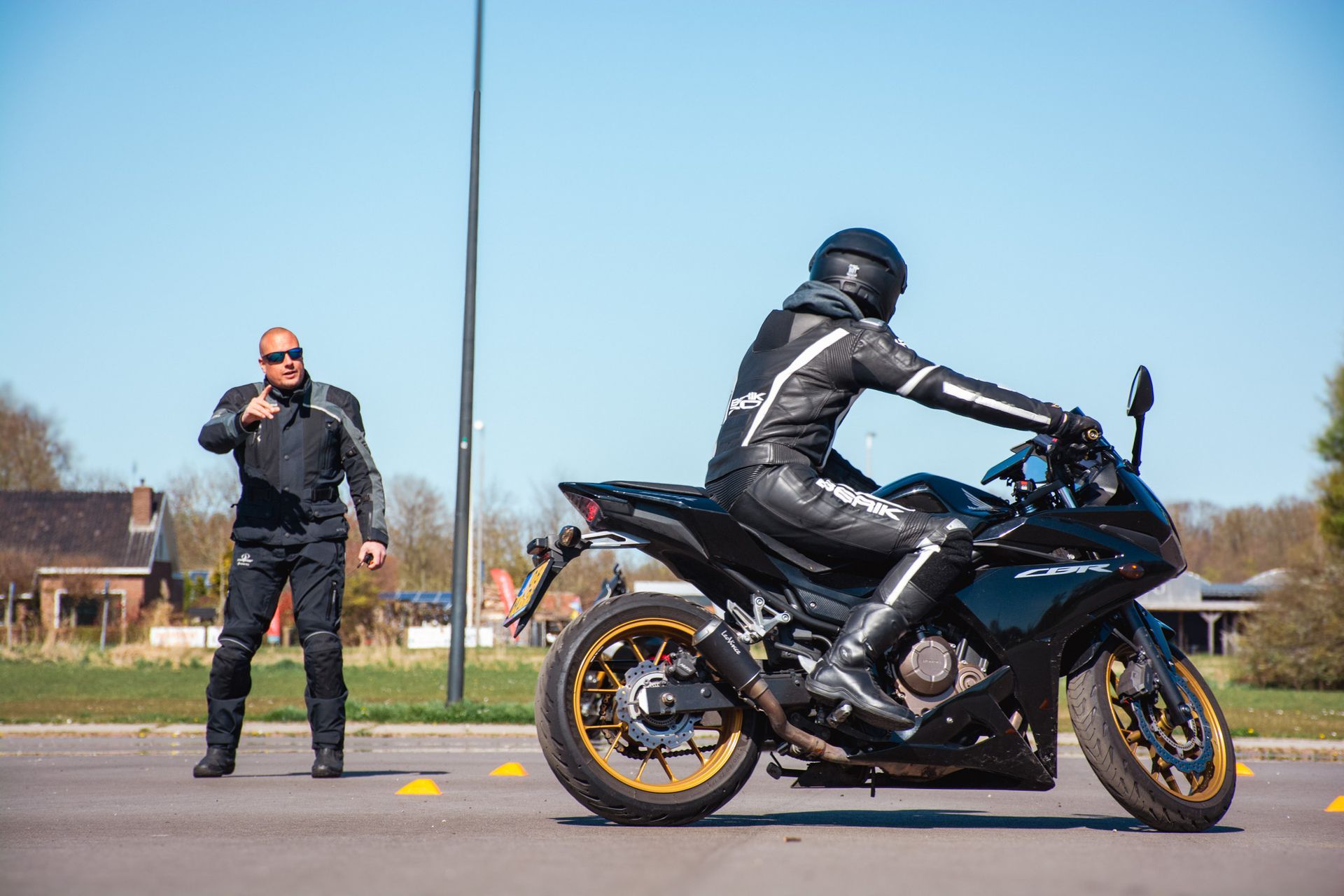 Een man staat naast een man die op een motorfiets rijdt.