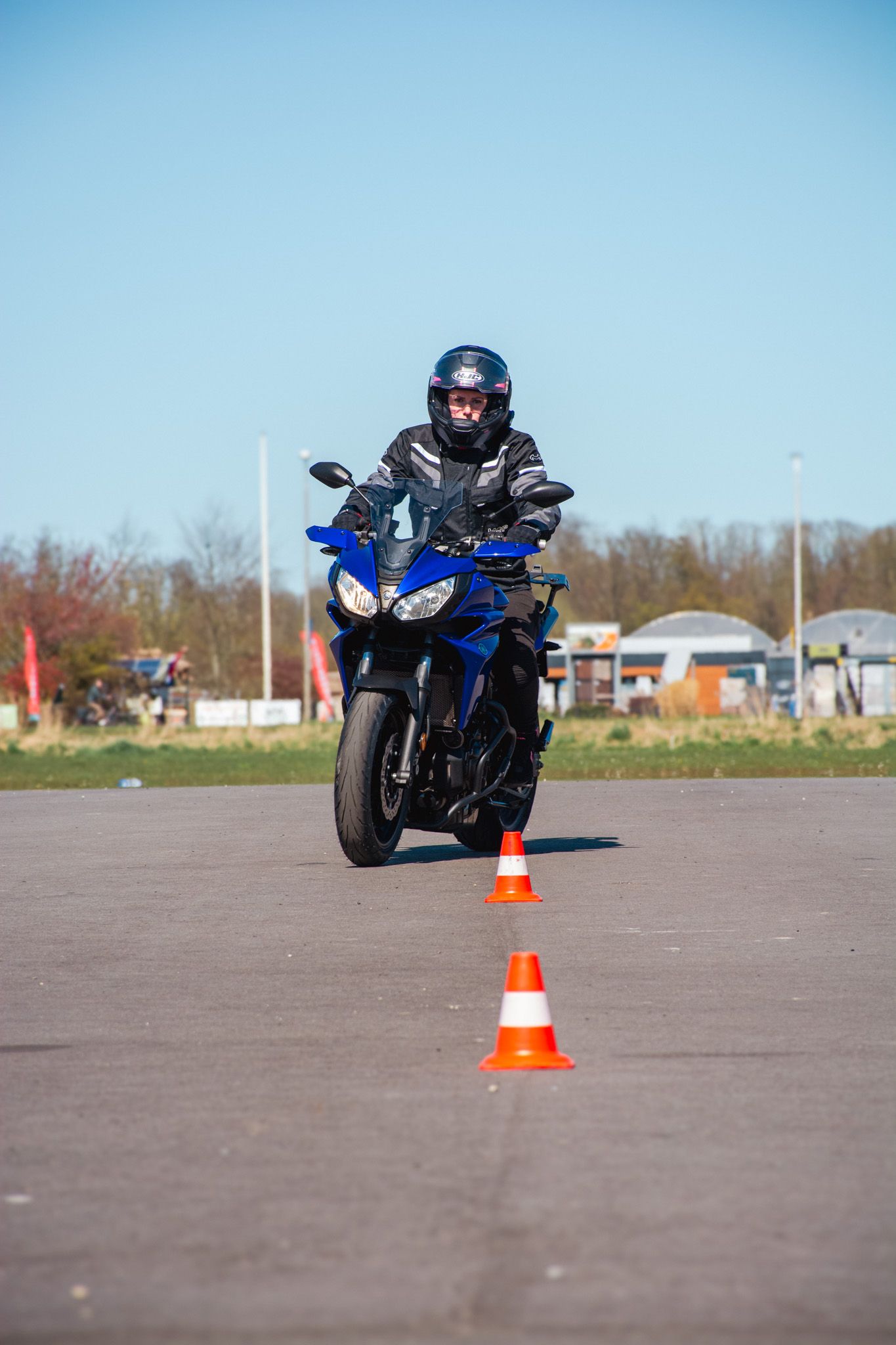 Een man rijdt op een motorfiets op een weg naast kegels.