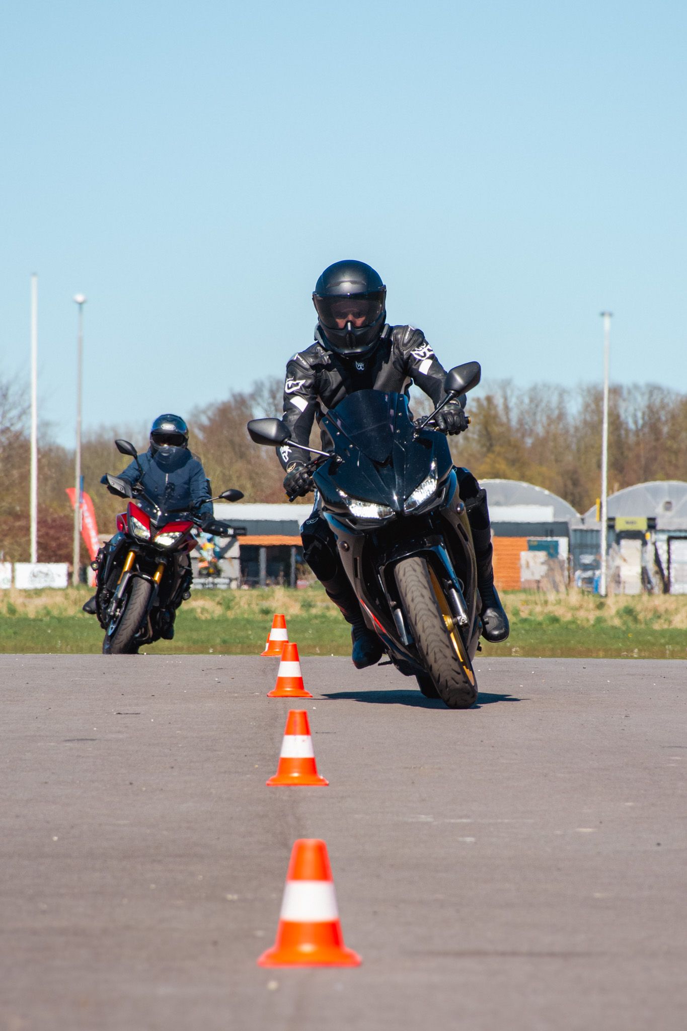 Een man rijdt op een motorfiets op een weg naast kegels.