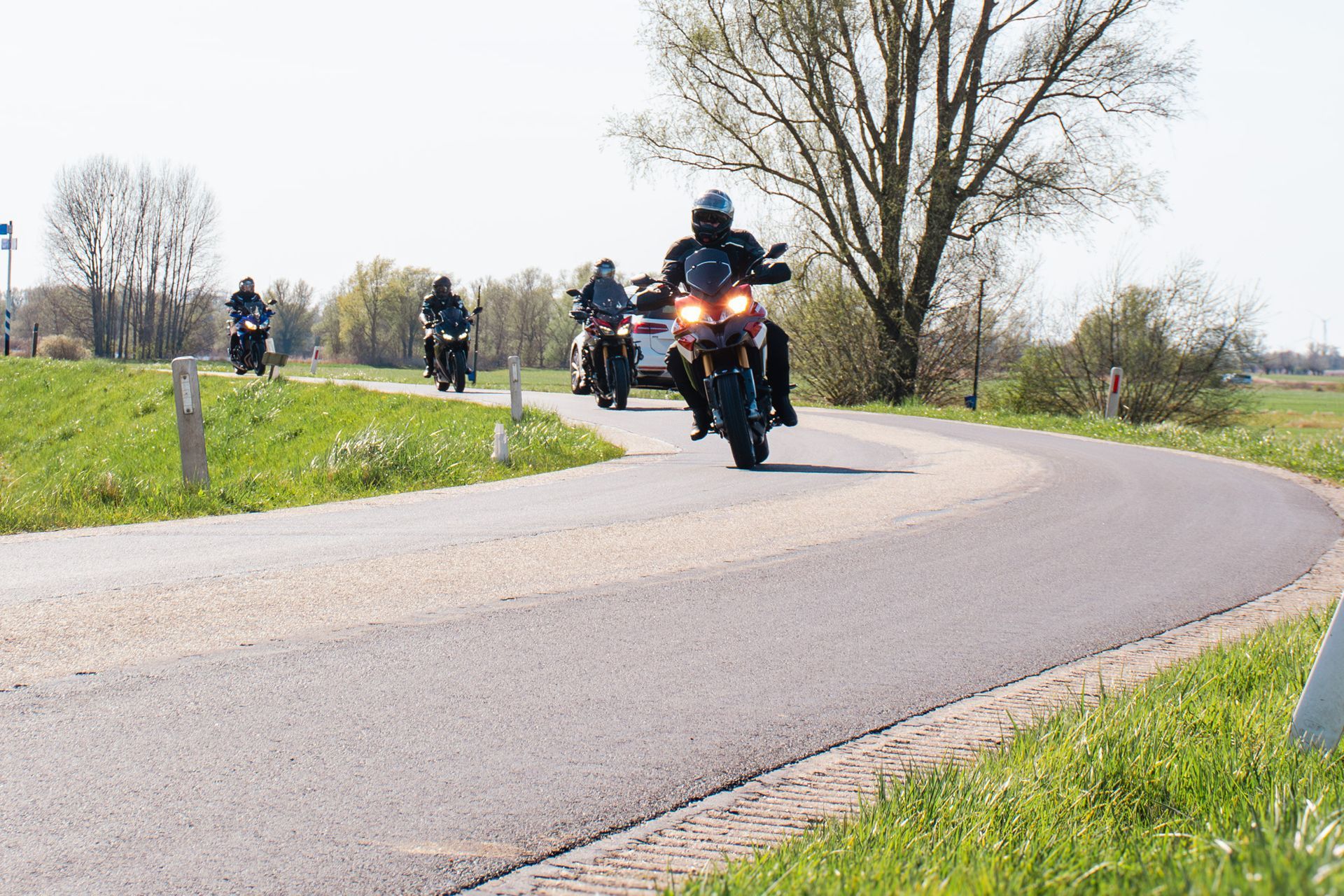 Een groep mensen rijdt op hun motorfiets over een bochtige weg.