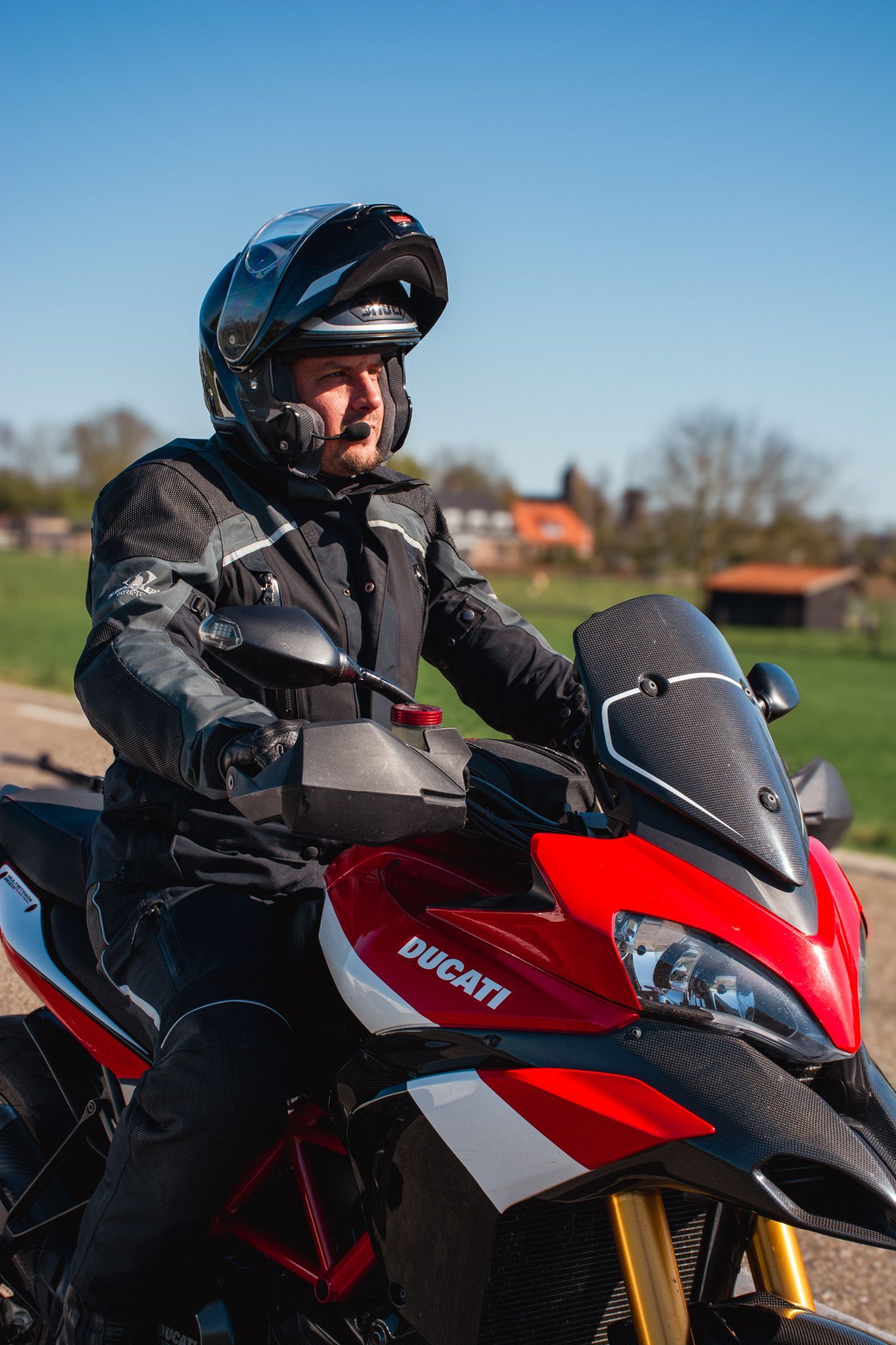 Een man rijdt op een rood-zwarte motorfiets op de weg.