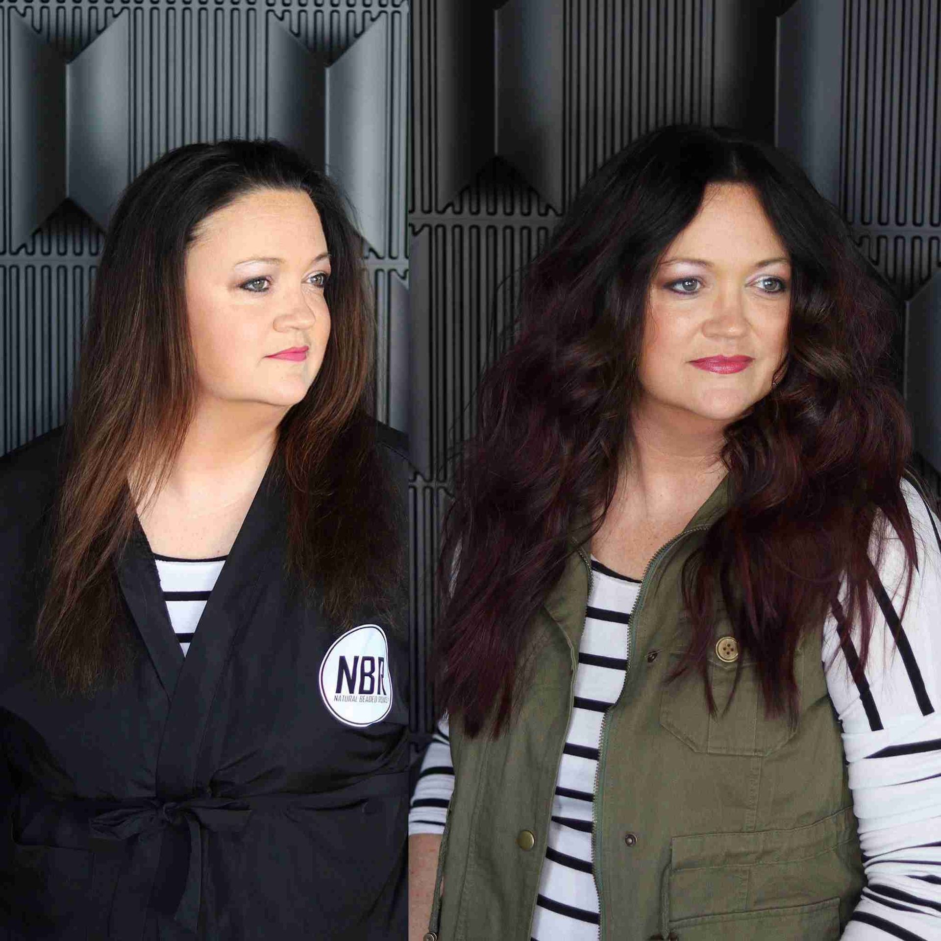 Two women are standing next to each other in front of a black wall.
