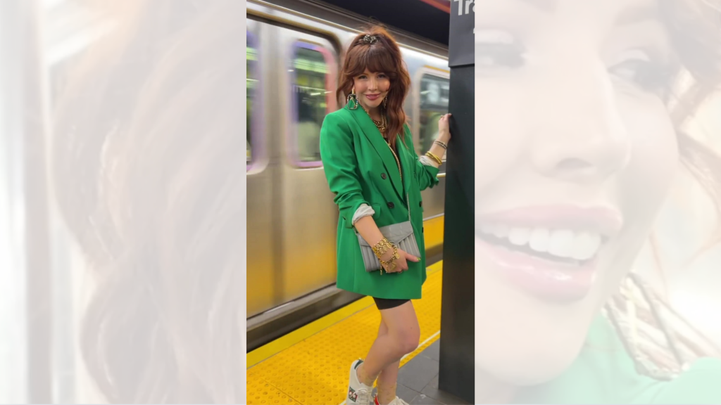 A woman in a green jacket is standing on a train platform.