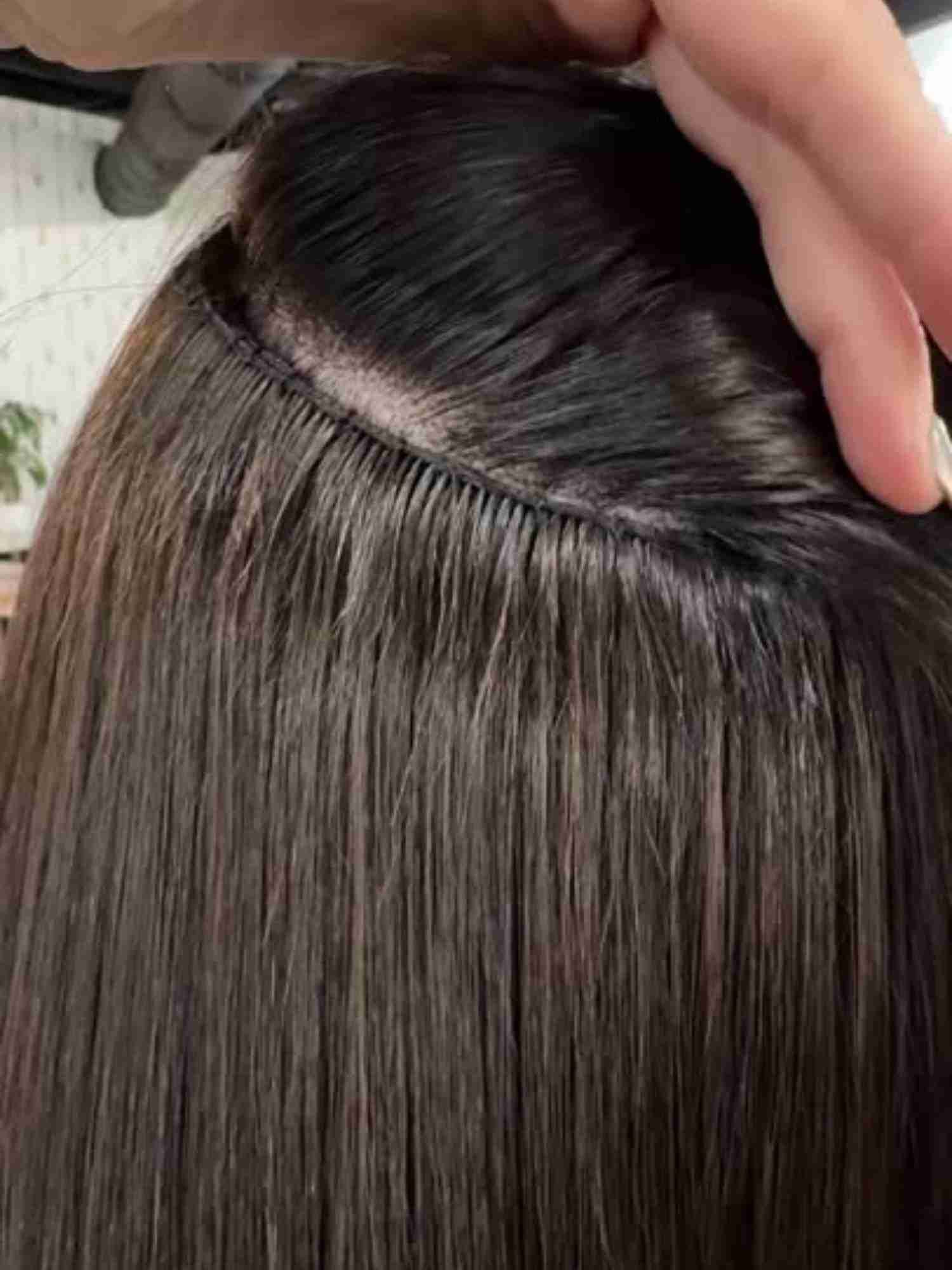 A person is holding a piece of hair in their hand.
