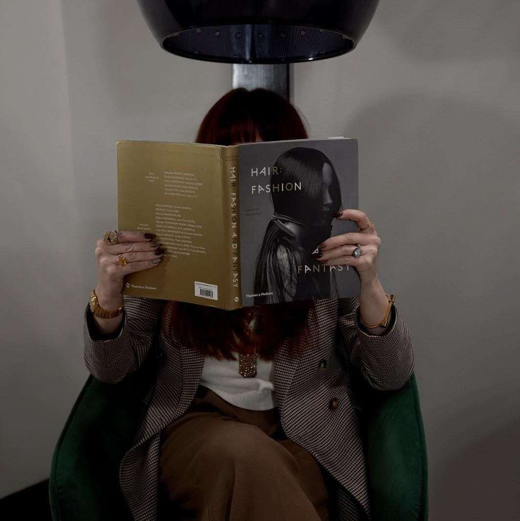 A woman is sitting in a chair reading a book