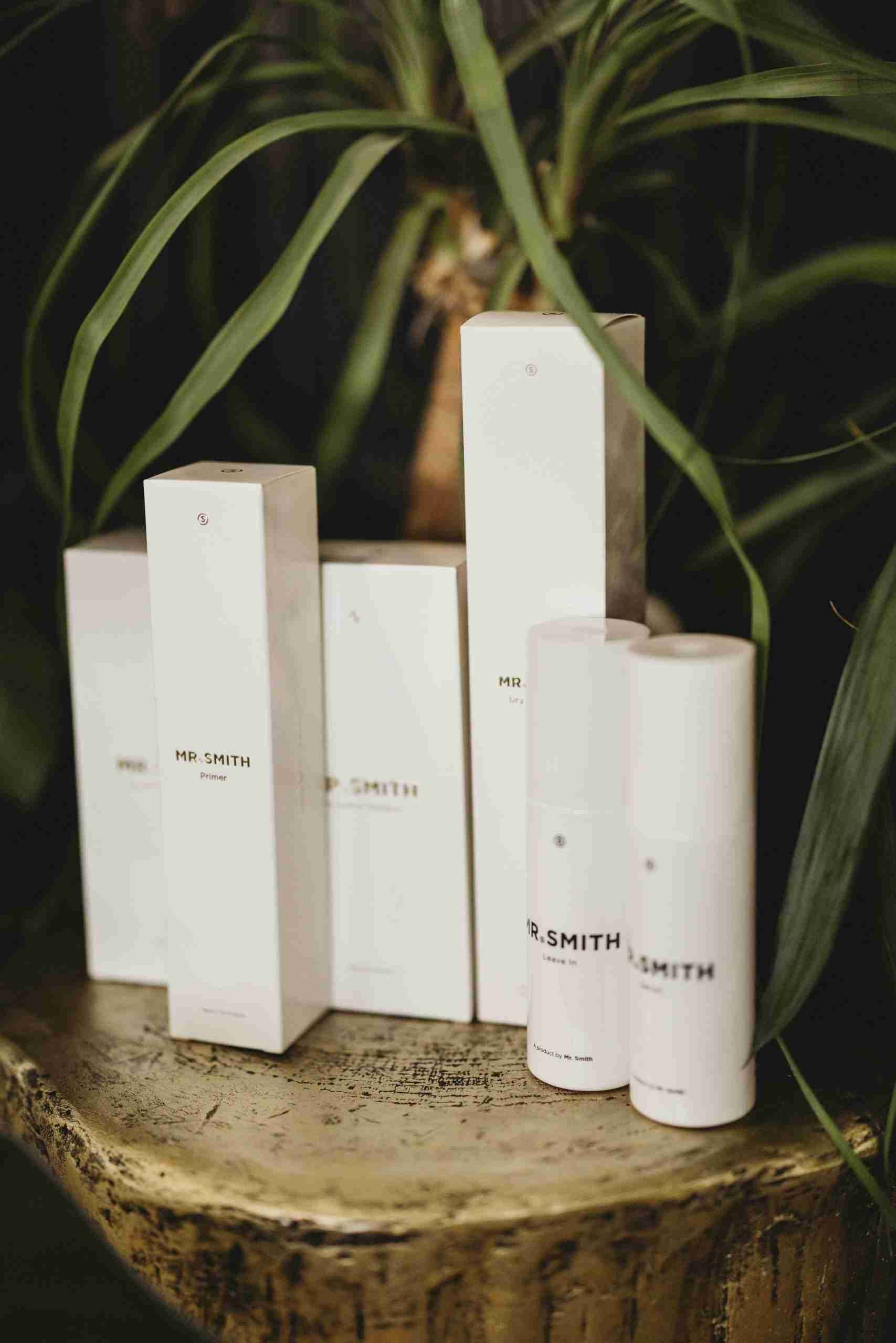 A group of white bottles and boxes are sitting on top of a wooden stump.