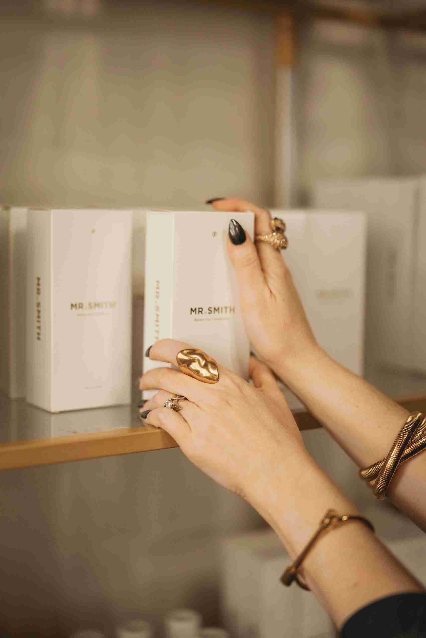 A woman is reaching for a box on a shelf.