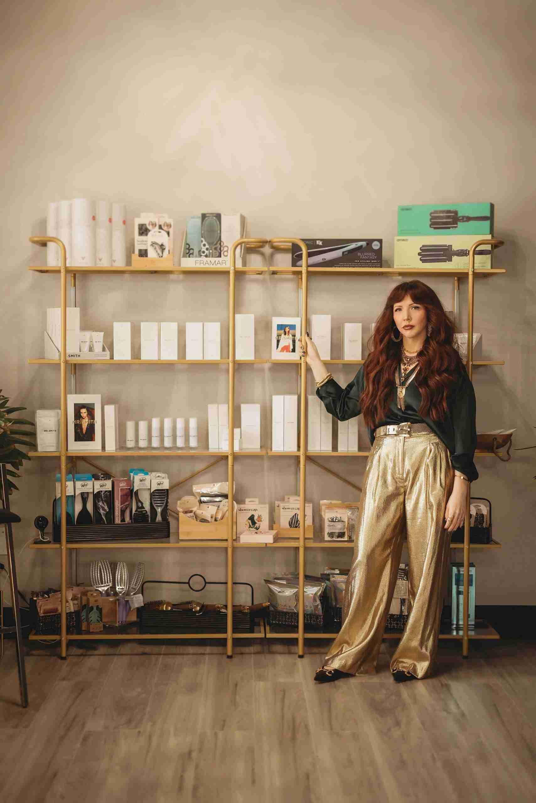 A woman in gold pants is standing in front of a bookshelf.