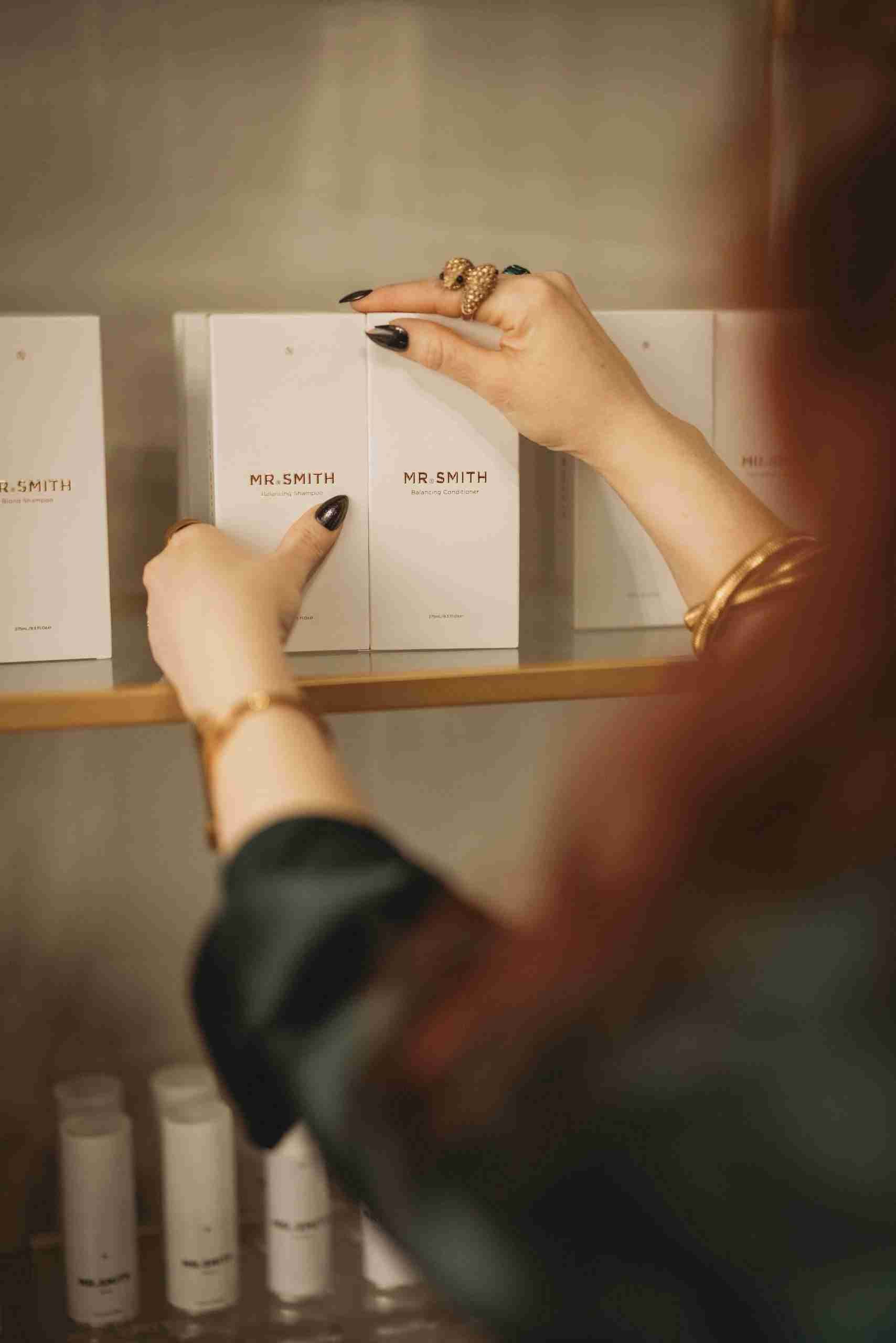 A woman is reaching for a box on a shelf in a store.