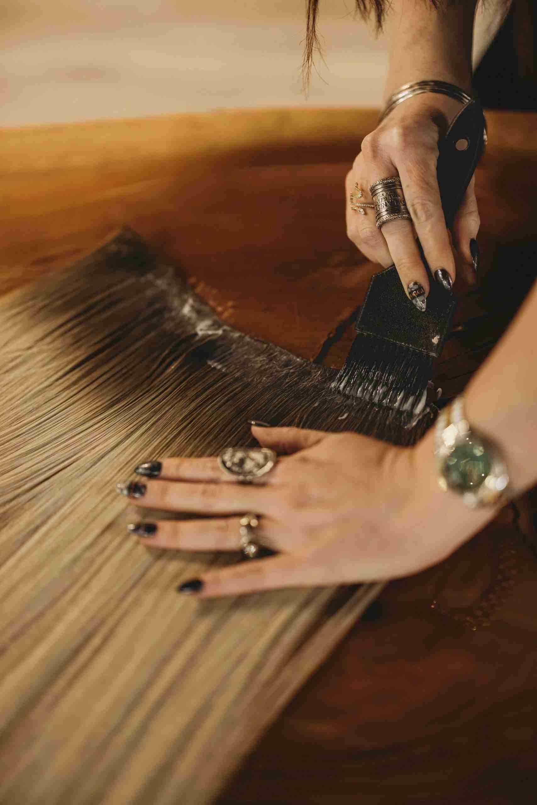 A woman is painting a piece of wood with a brush.