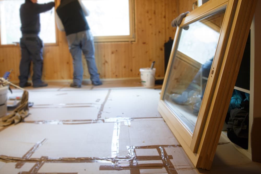 Two Men Are Installing a Window in A Room — Distinctive Glass & Aluminium in Port Kembla, NSW