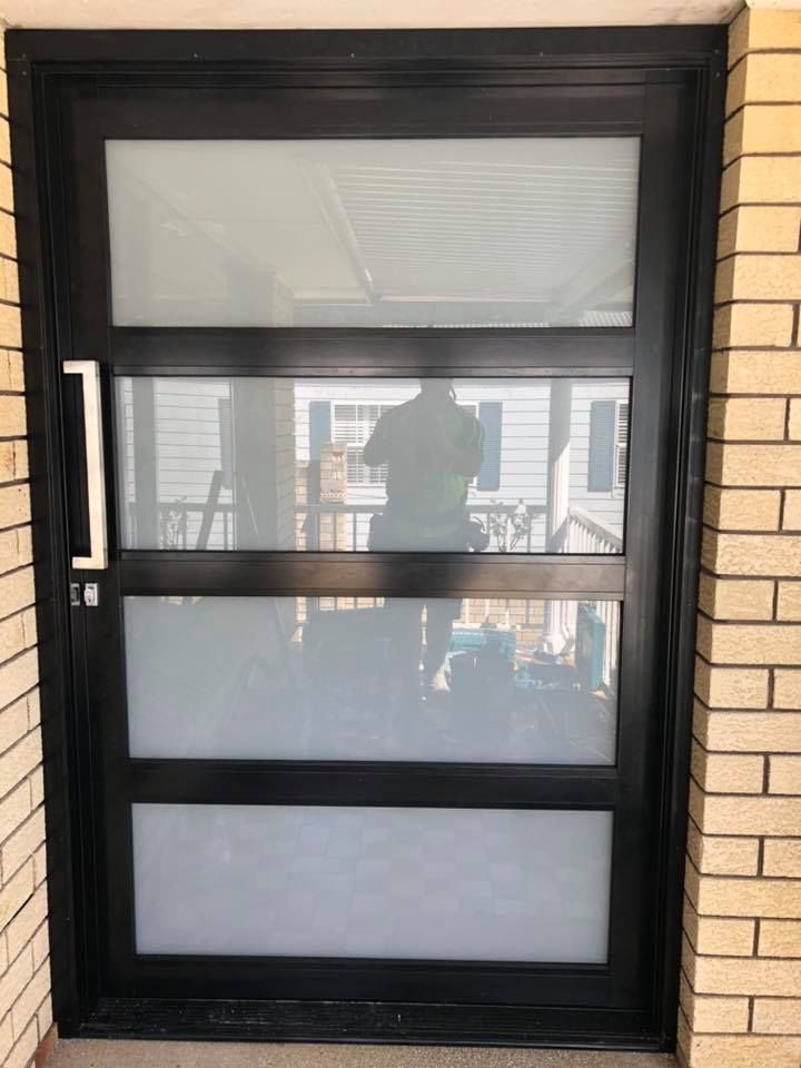 A Black Door with A White Handle Is on A Brick Wall — Distinctive Glass & Aluminium in Albion Park, NSW