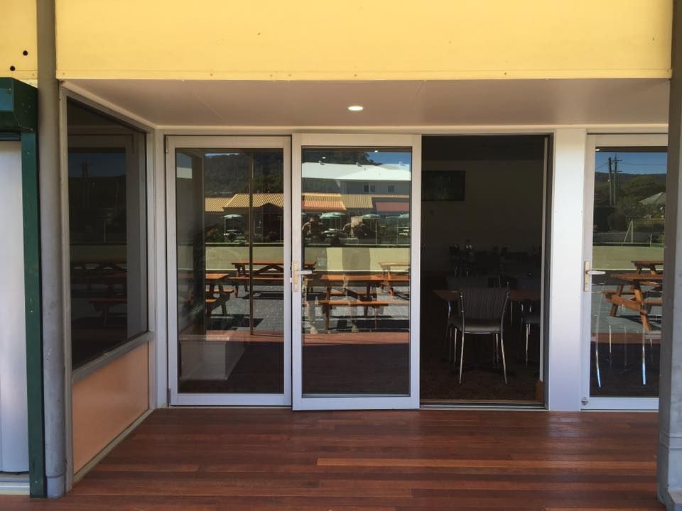 Glass Doors Leading Out To A Wooden Deck — Distinctive Glass & Aluminium in Port Kembla, NSW