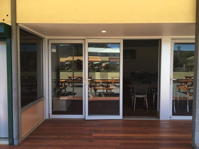 Glass Doors Leading Out To A Wooden Deck — Distinctive Glass & Aluminium in Port Kembla, NSW