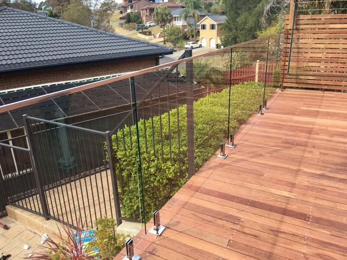 A Wooden Deck with A Glass Railing and A House — Distinctive Glass & Aluminium in Port Kembla, NSW