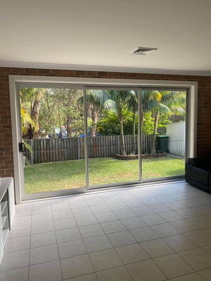 Three large glass sliding doors with a backyard and trees — Distinctive Glass & Aluminium in Port Kembla, NSW
