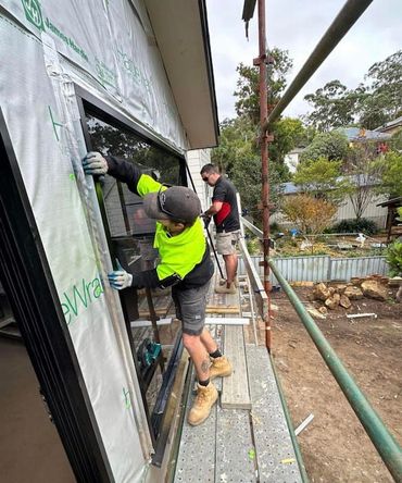 A Group of Men Are Working on A Building — Distinctive Glass & Aluminium in Port Kembla, NSW