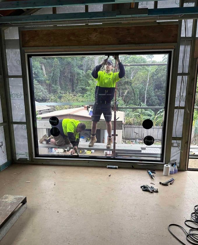 A Group of Men Are Working on A Window in A Room — Distinctive Glass & Aluminium in Port Kembla, NSW