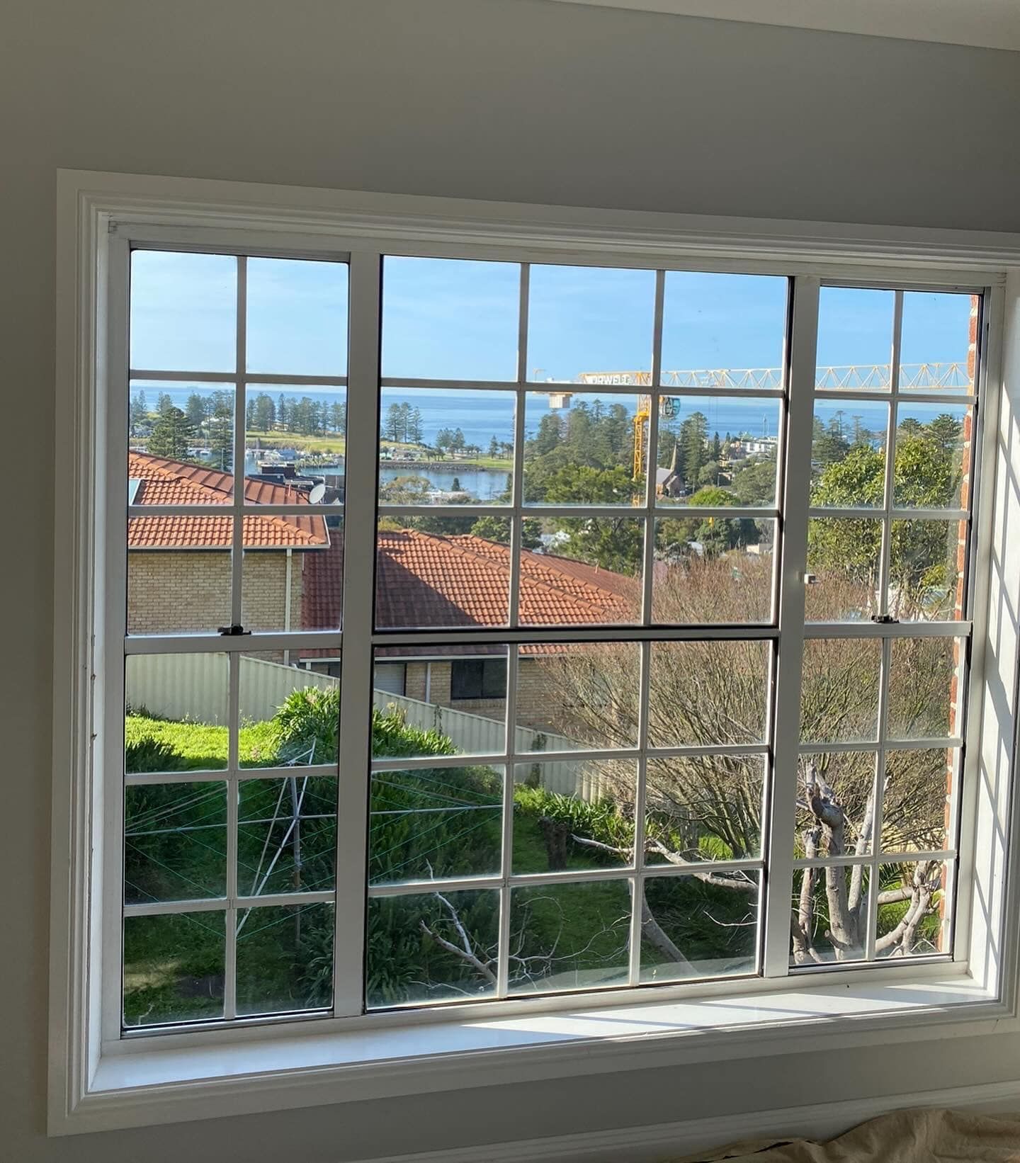 A white panelled window overlooking a house and the ocean — Distinctive Glass & Aluminium in Port Kembla, NSW