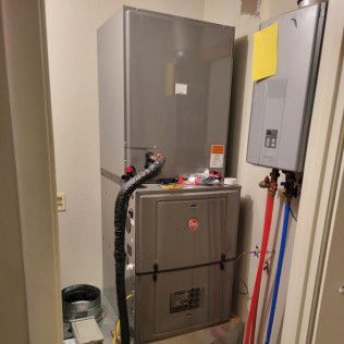Furnace and water heater in a utility closet. Gray and silver appliances with visible plumbing.