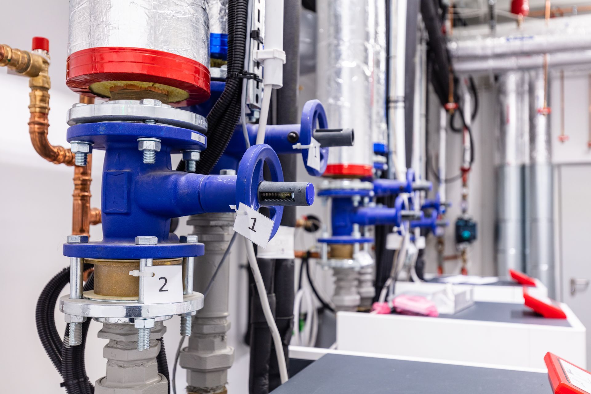 Blue valves and insulated pipes in a mechanical room.