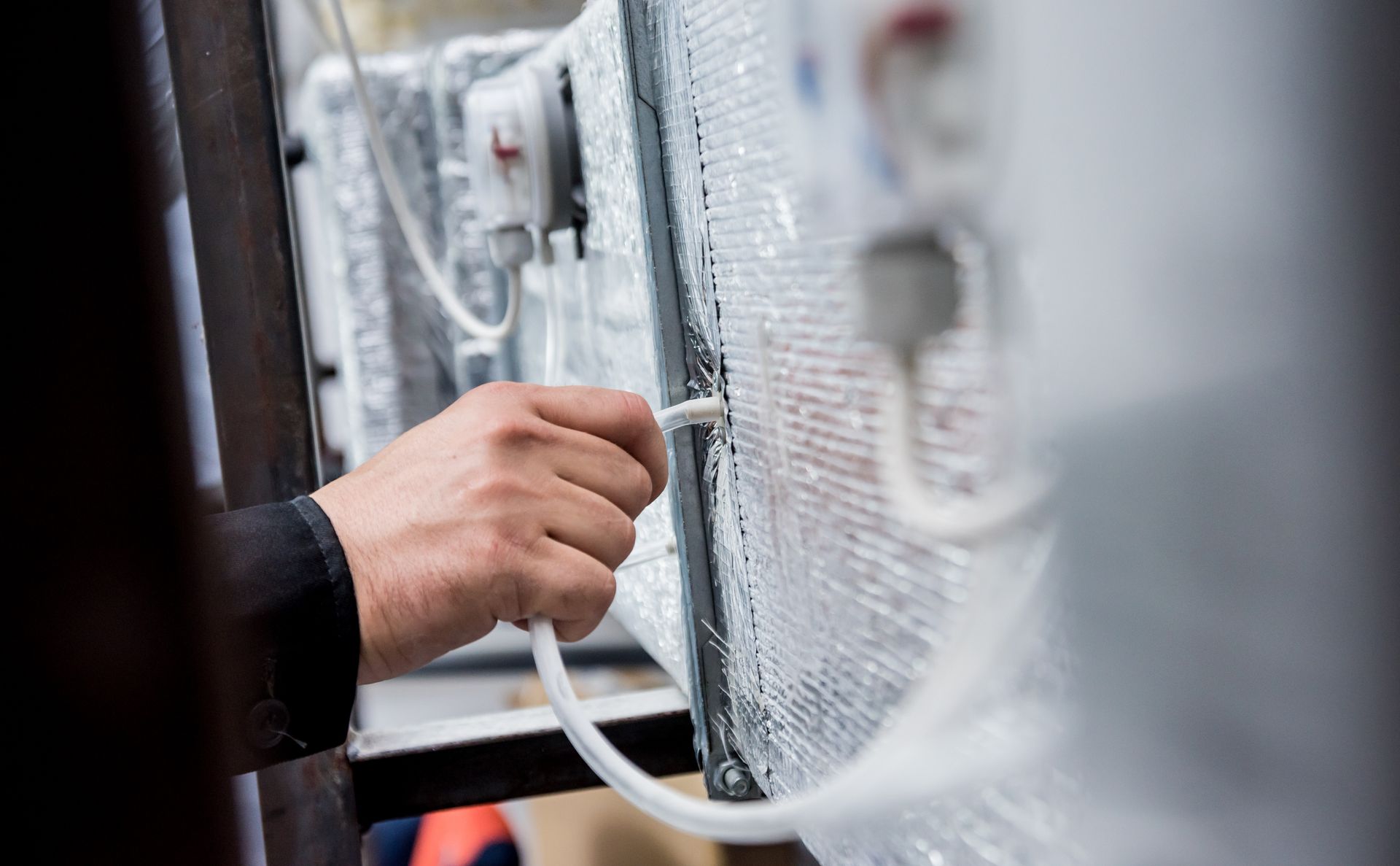 A person's hand connecting a white tube to a medical device, close-up shot.
